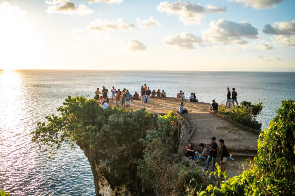 Locals beobachten den Sonnenuntergang am Balangan Beach Cliff