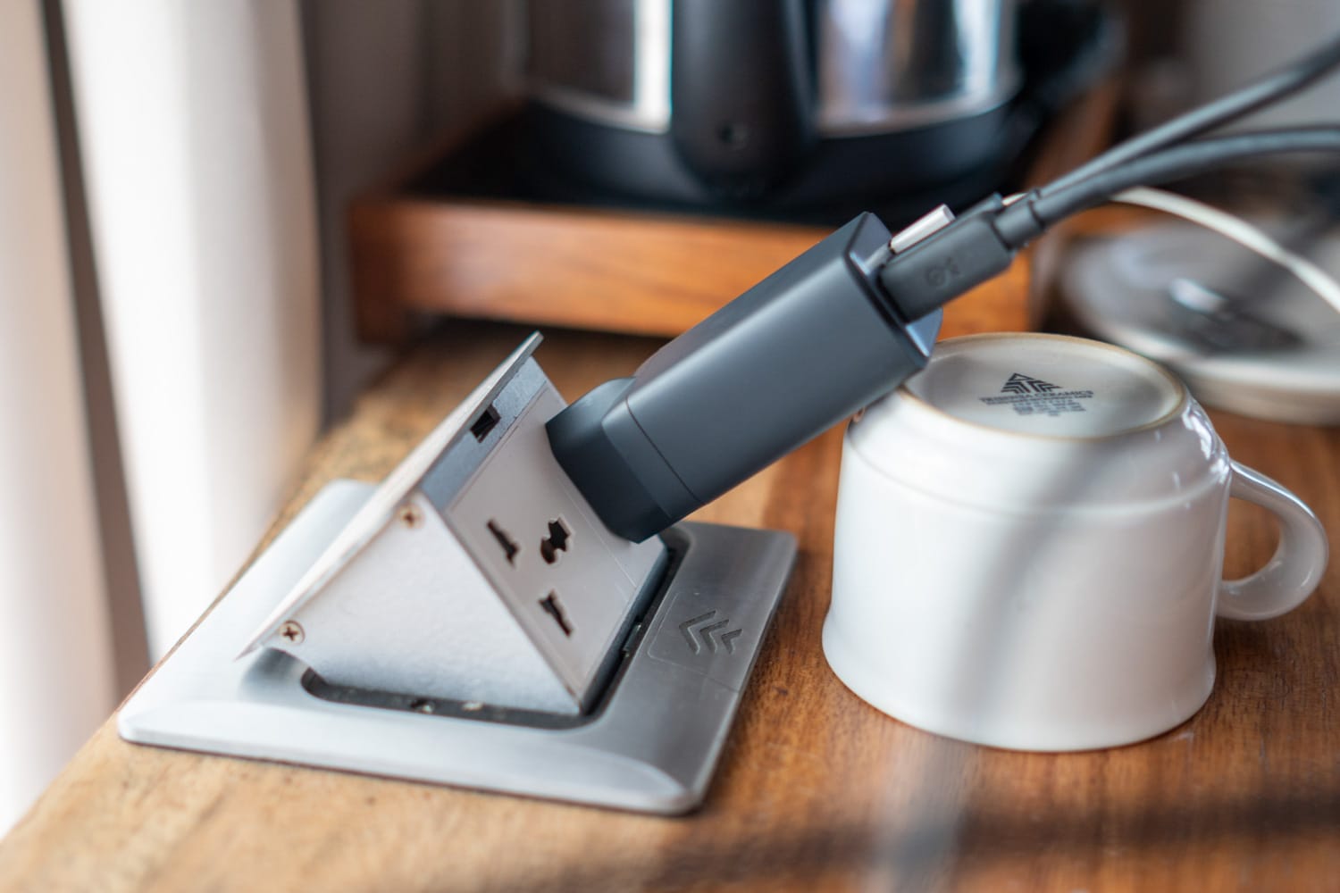 Tasse stabilisiert ein Ladegerät in einer ausgeleierten Steckdose auf Bali in Indonesien