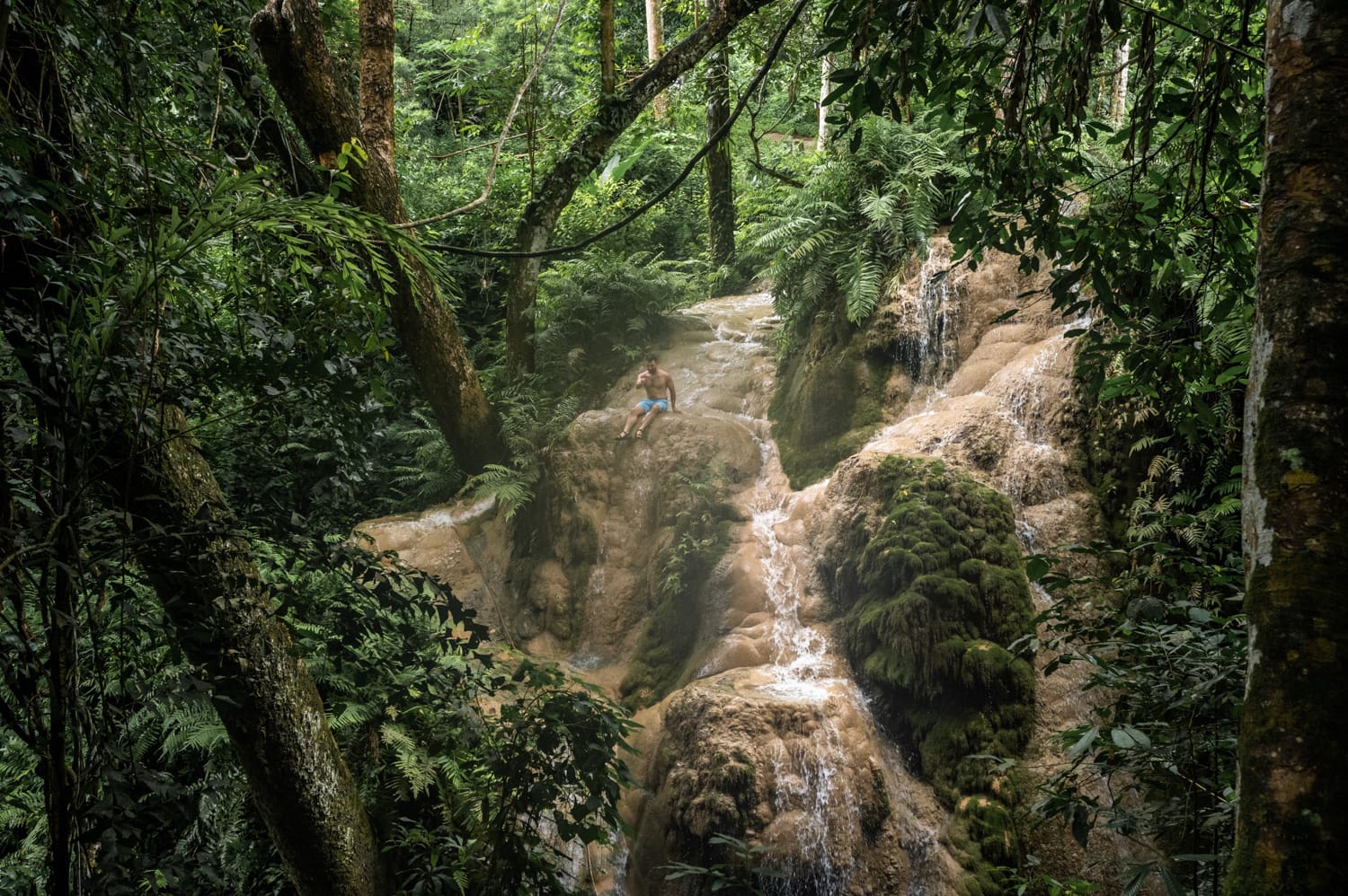 Mann klettert den Bua Tong Sticky Waterfall hinauf
