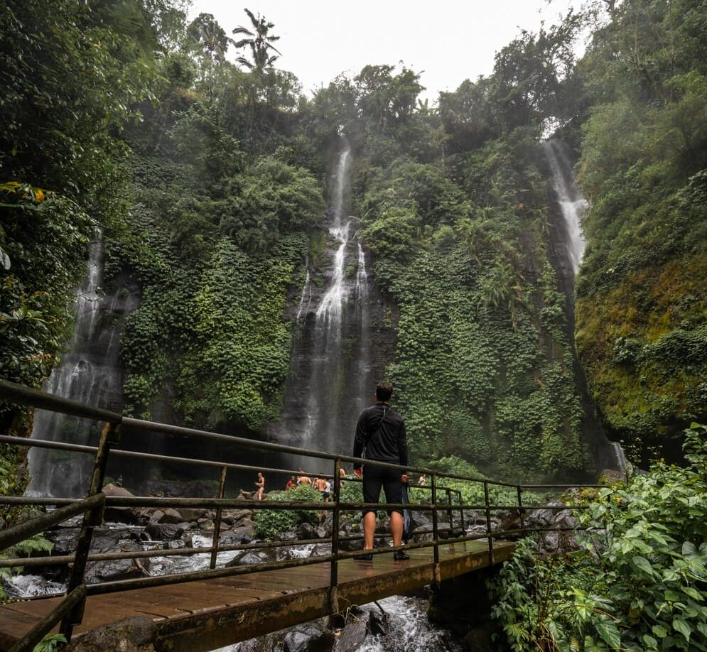 Nils Alexander Kemna läuft über eine Brücke auf den Fiji Wasserfall auf Bali zu
