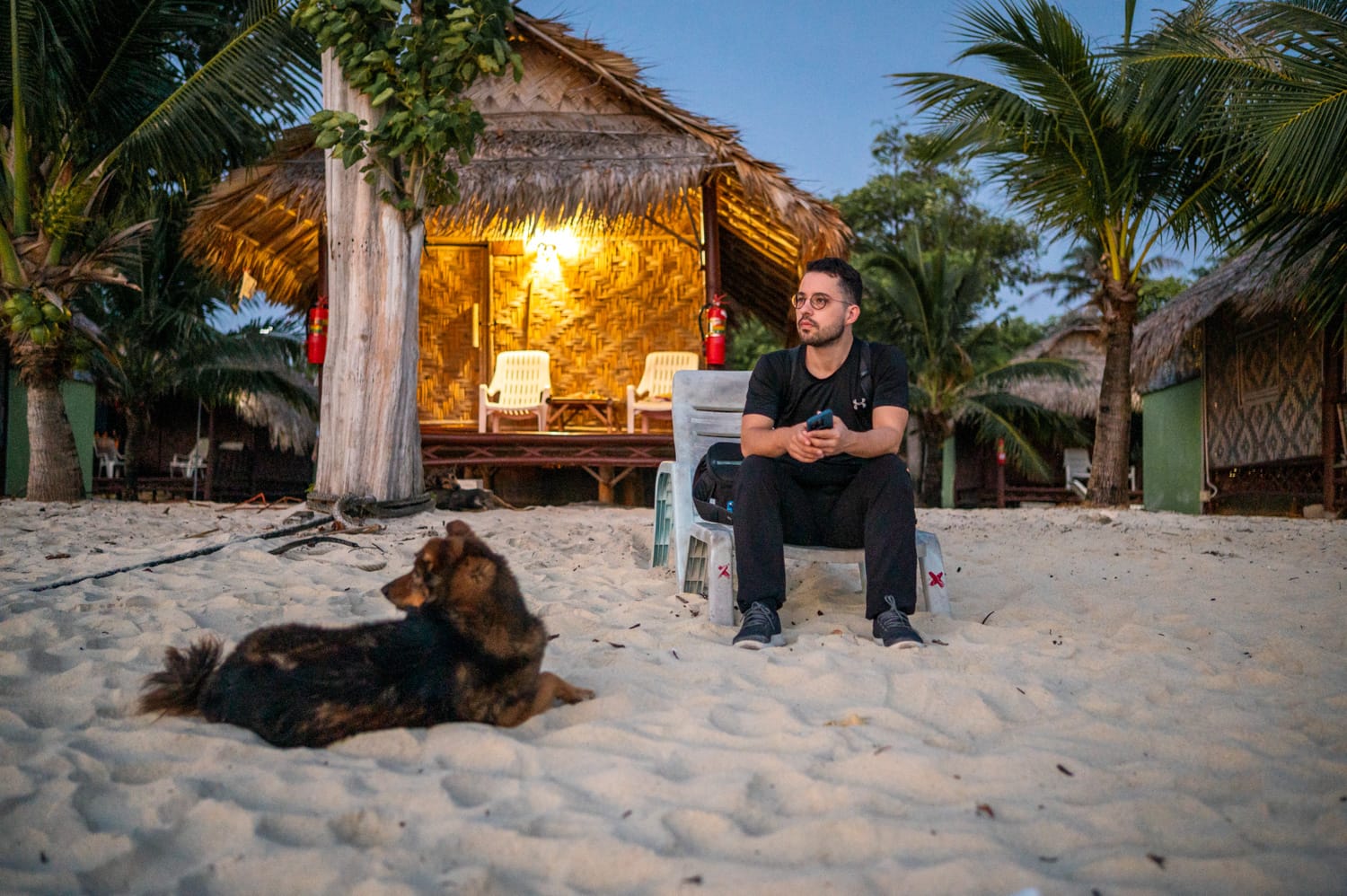 Nils Alexander Kemna und ein Hund beobachten den Sonnenaufgang vor einer einfachen Bambushütte am Sunrise Beach auf Koh Lipe