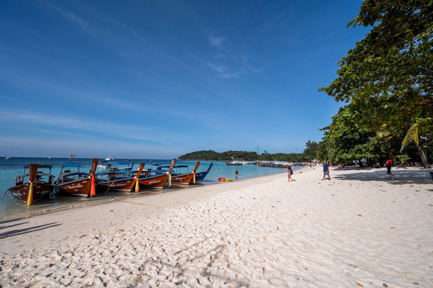 Longtailboote ankern am Strand vor den Bundhaya Villas am Pattaya Beach auf Koh Lipe