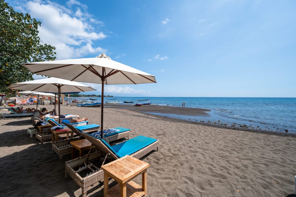 Sonnenliegen und badende Urlauber am Pantai Lovina Beach