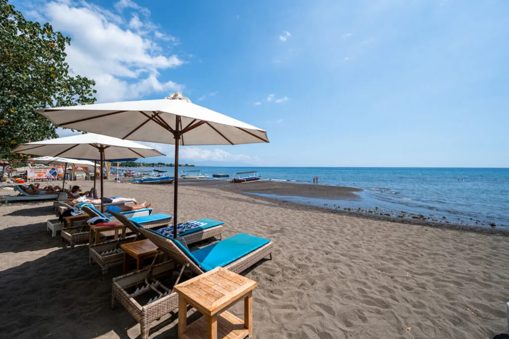 Sonnenliegen und badende Urlauber am Pantai Lovina Beach