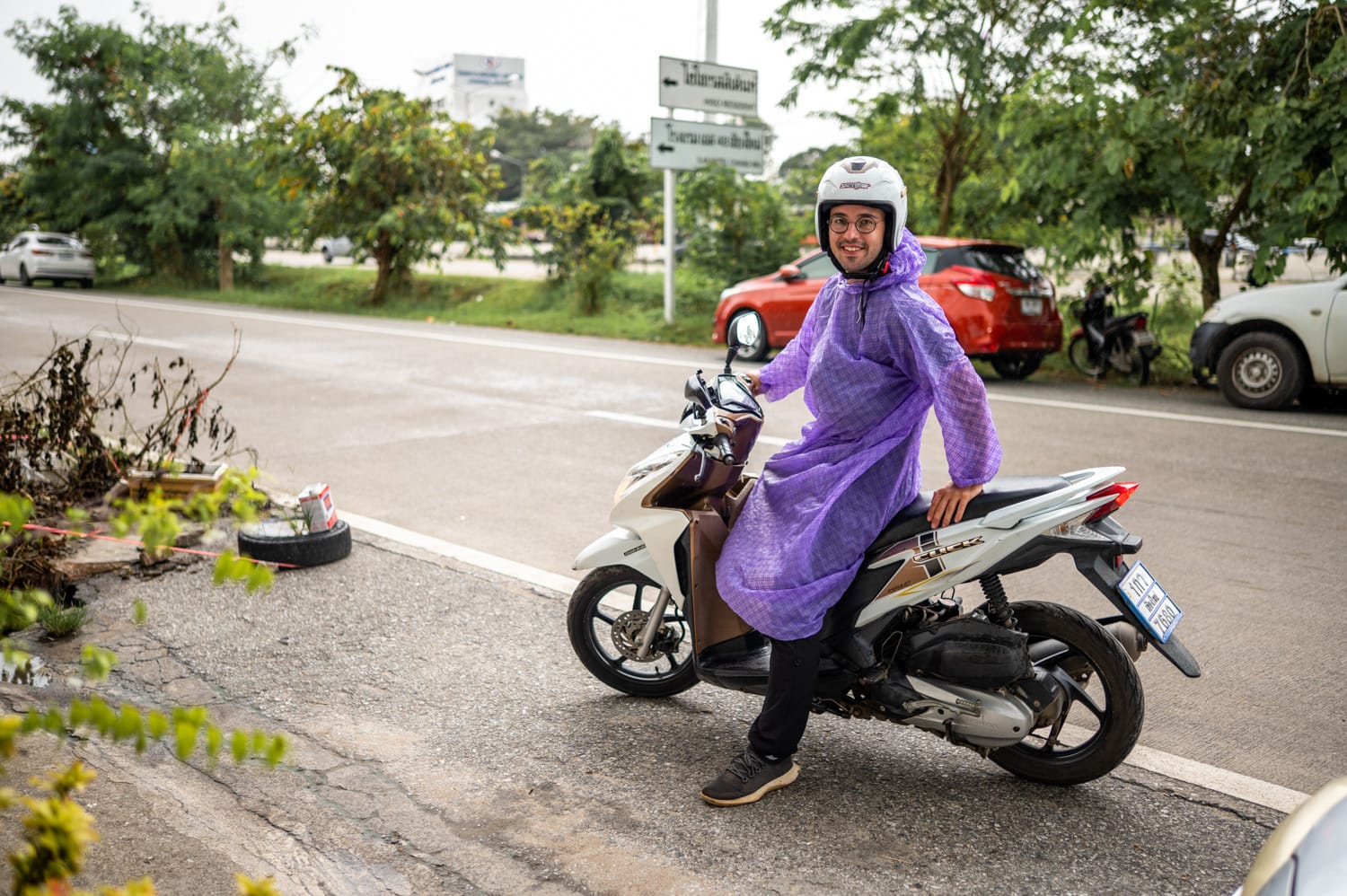 Nils Alexander Kemna trägt ein Regencape beim Roller fahren in Thailand