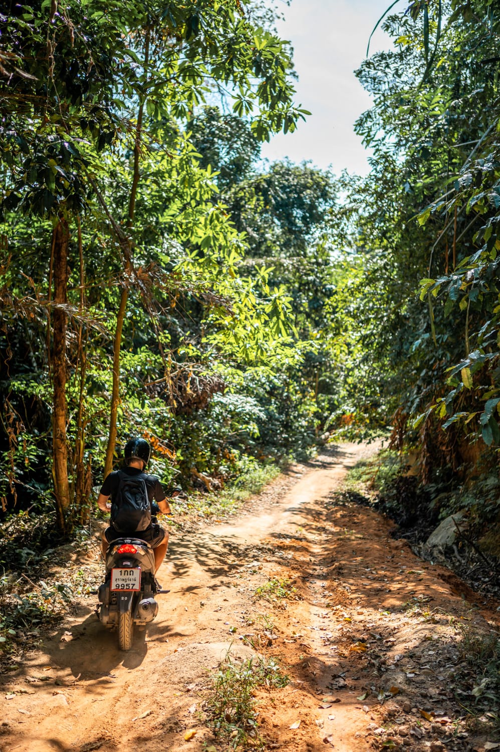 Nils Alexander Kemna fährt Roller auf einer unbefestigten Straße in Thailand