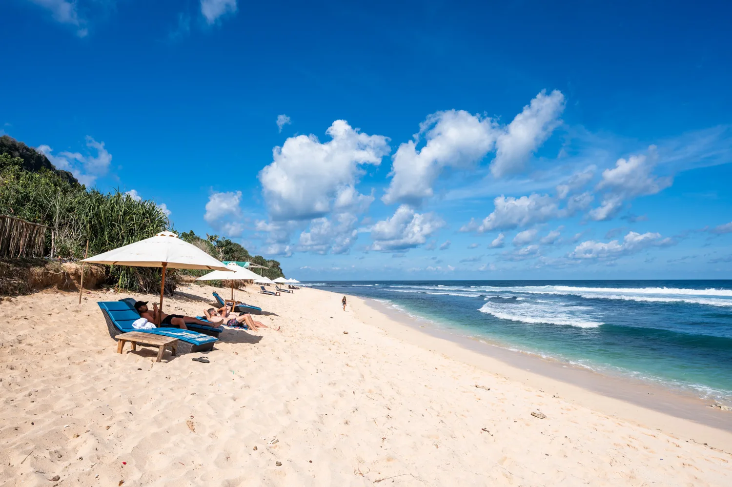 Sonnenliegen und weißer Sand am Nunggalan Beach