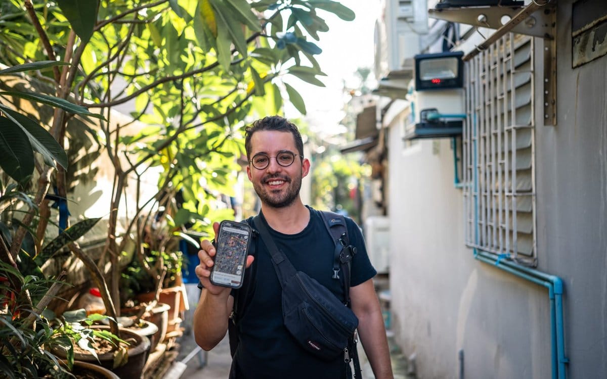 Alex zeigt in einer ruhigen Gasse in Bangkok die Karte auf dem Handy