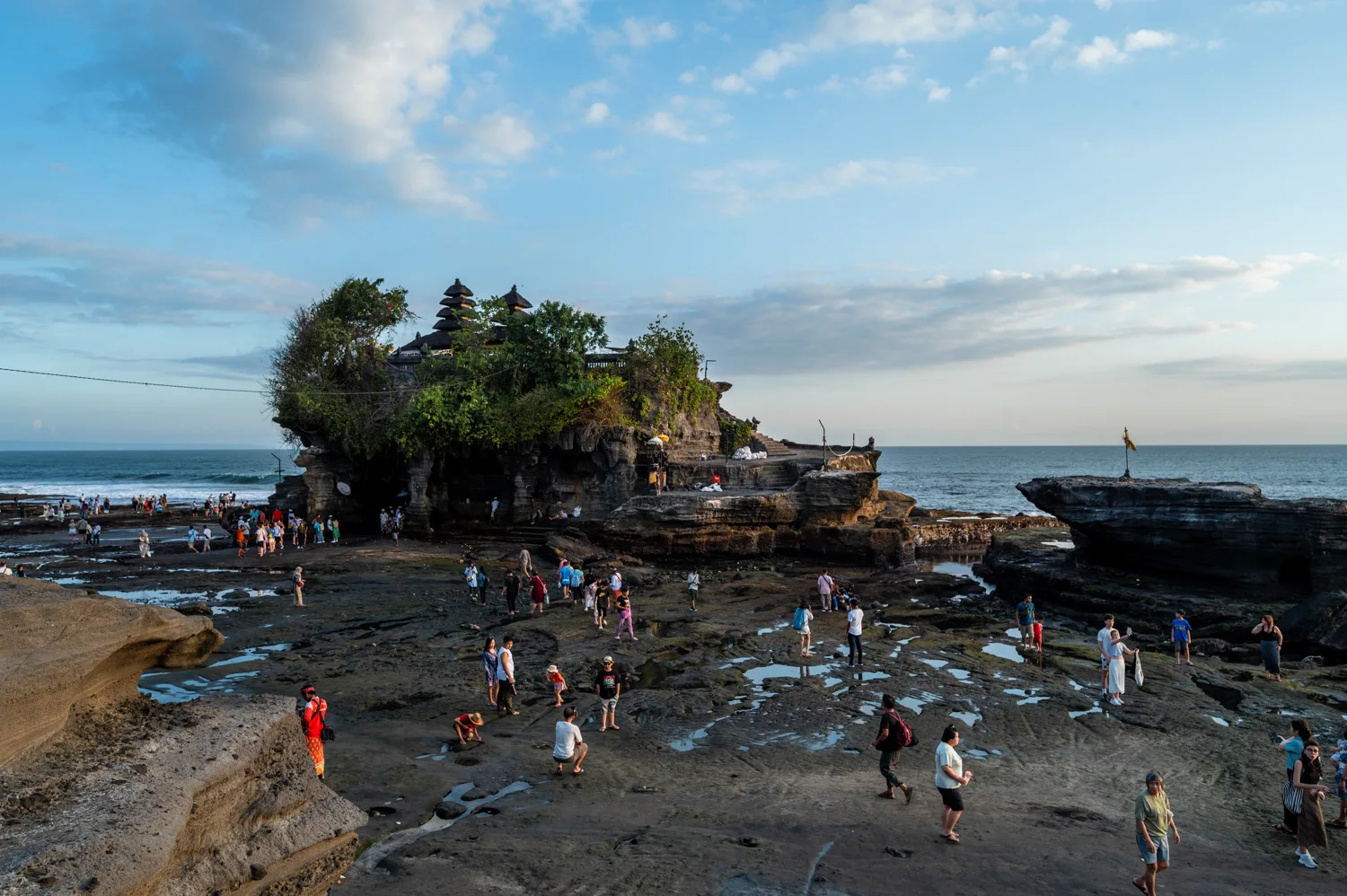 Touristen laufen bei Ebbe zum Meerestempel Pura Tanah Lot