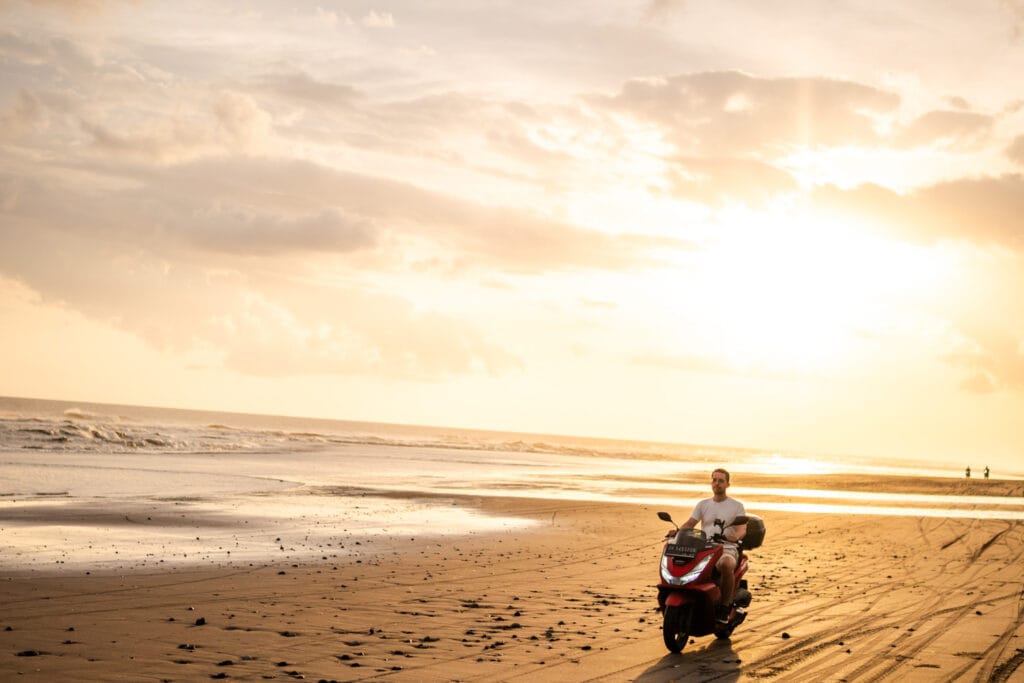 Alex fährt mit unserem großen Roller auf dem Pasut Beach