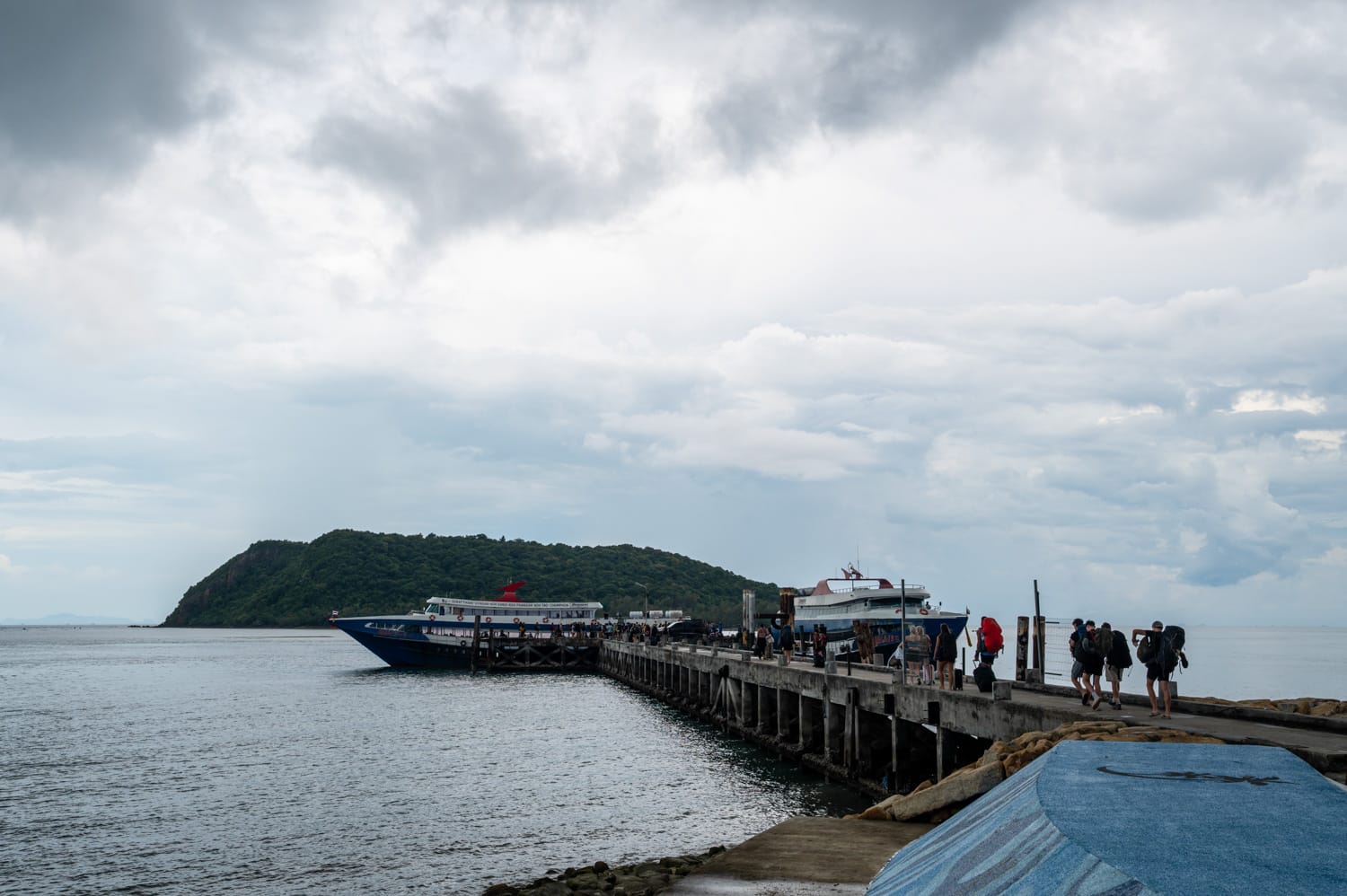 Backpacker laufen an einem Pier mit großen Fähren entlang auf dem Weg nach Koh Phangan