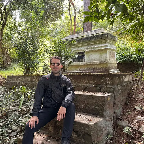 Alex sitzt am Grab des französischen Forschers Henri Mouhot im Wald bei Luang Prabang in Laos