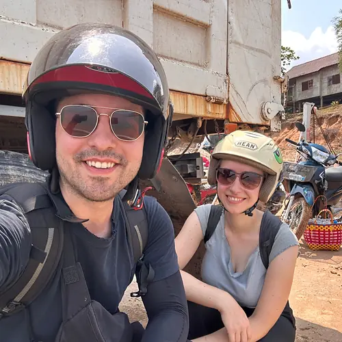 Vanessa und Alex mit Helmen auf einer Fähre über den Mekong bei Champasak in Laos, hinter ihnen ein Lastwagen