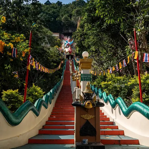 Lange Treppe mit Naga-Schlangen als Geländer hinauf zu einem Tempel in Kanchanaburi