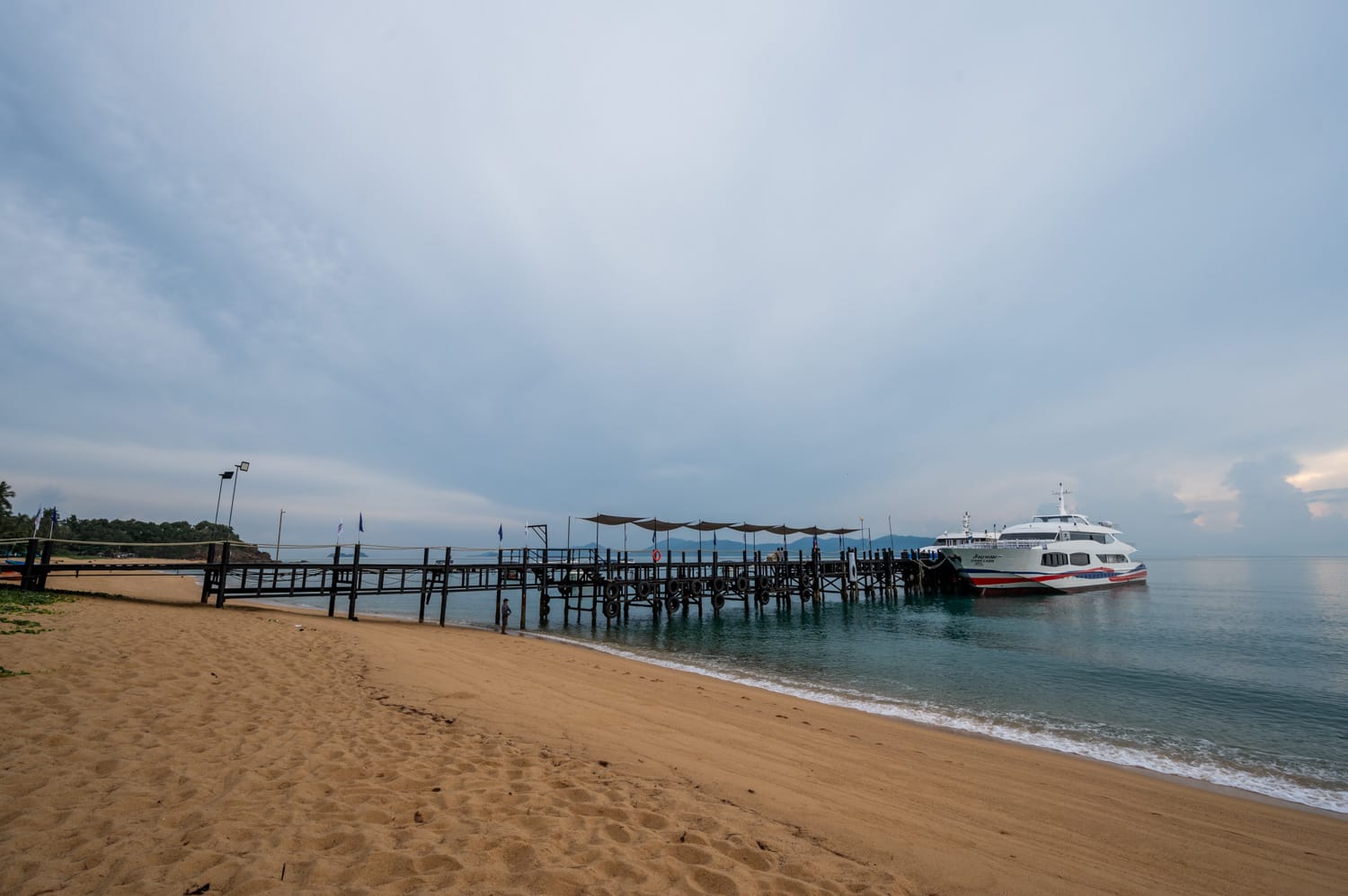 Katamaran-Fähre an einem Holzpier am Strand von Koh Samui bei bewölktem Himmel im Golf von Thailand