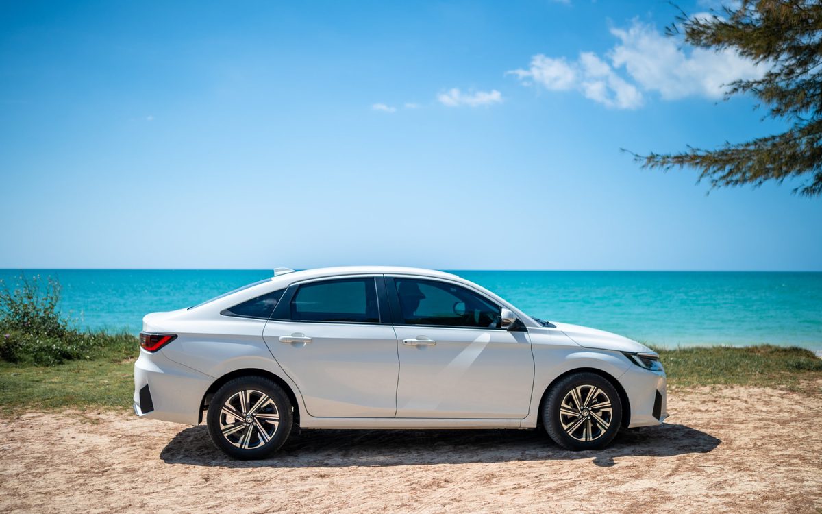 Auto am Strand vor türkisem Meer, unterwegs mit eigenem Fahrzeug