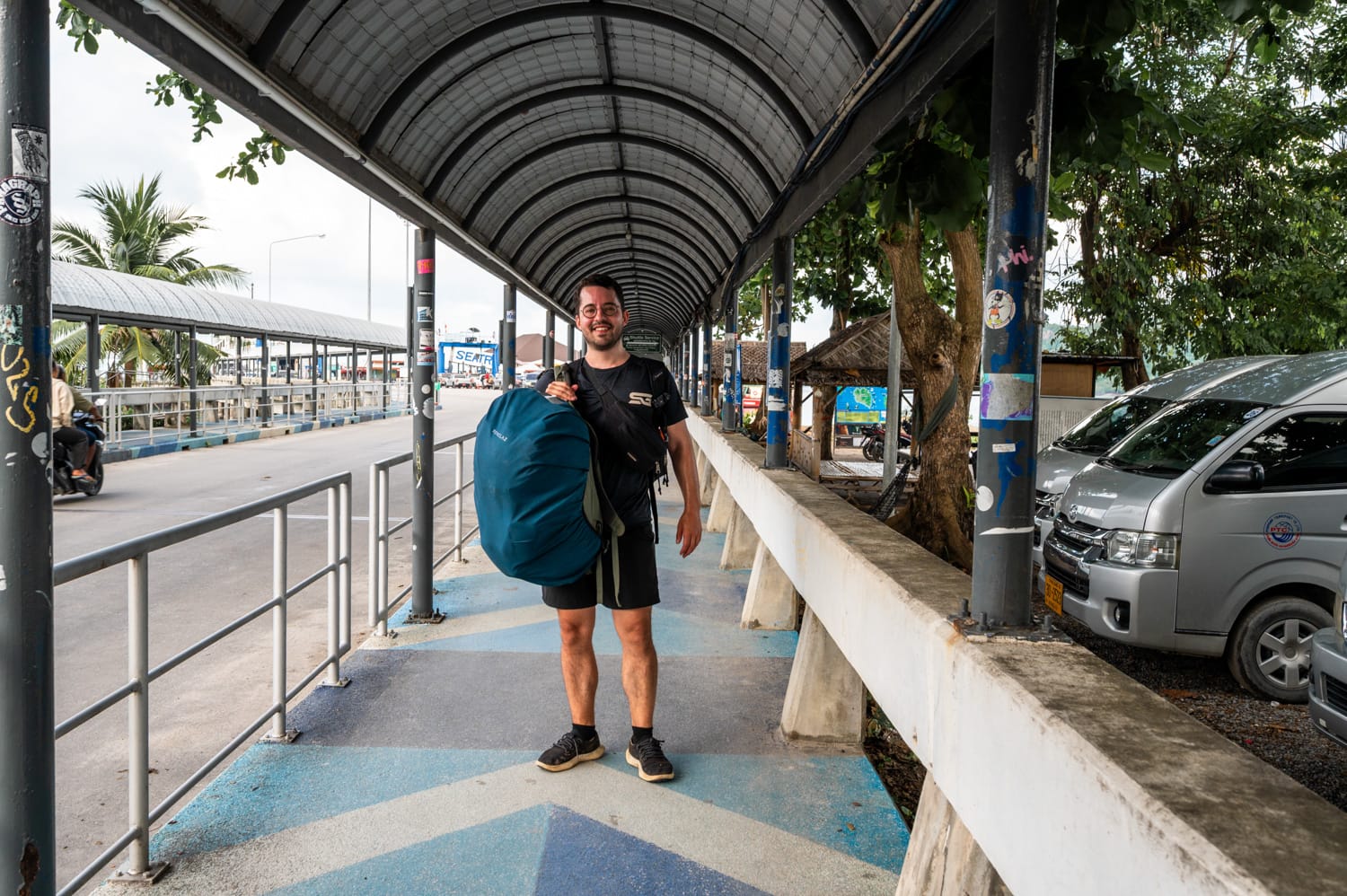 Nils Alexander Kemna mit Reiserucksack unter dem überdachten Gehweg am Pier auf dem Weg nach Koh Phangan