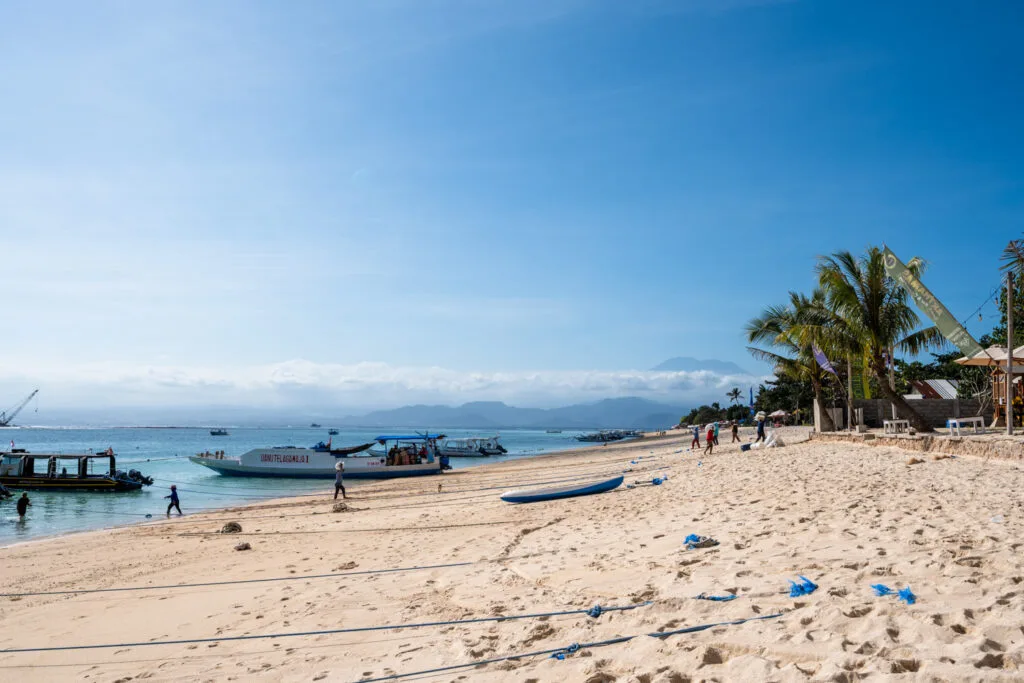 Arbeiter tragen Waren über den Jungutbatu Beach