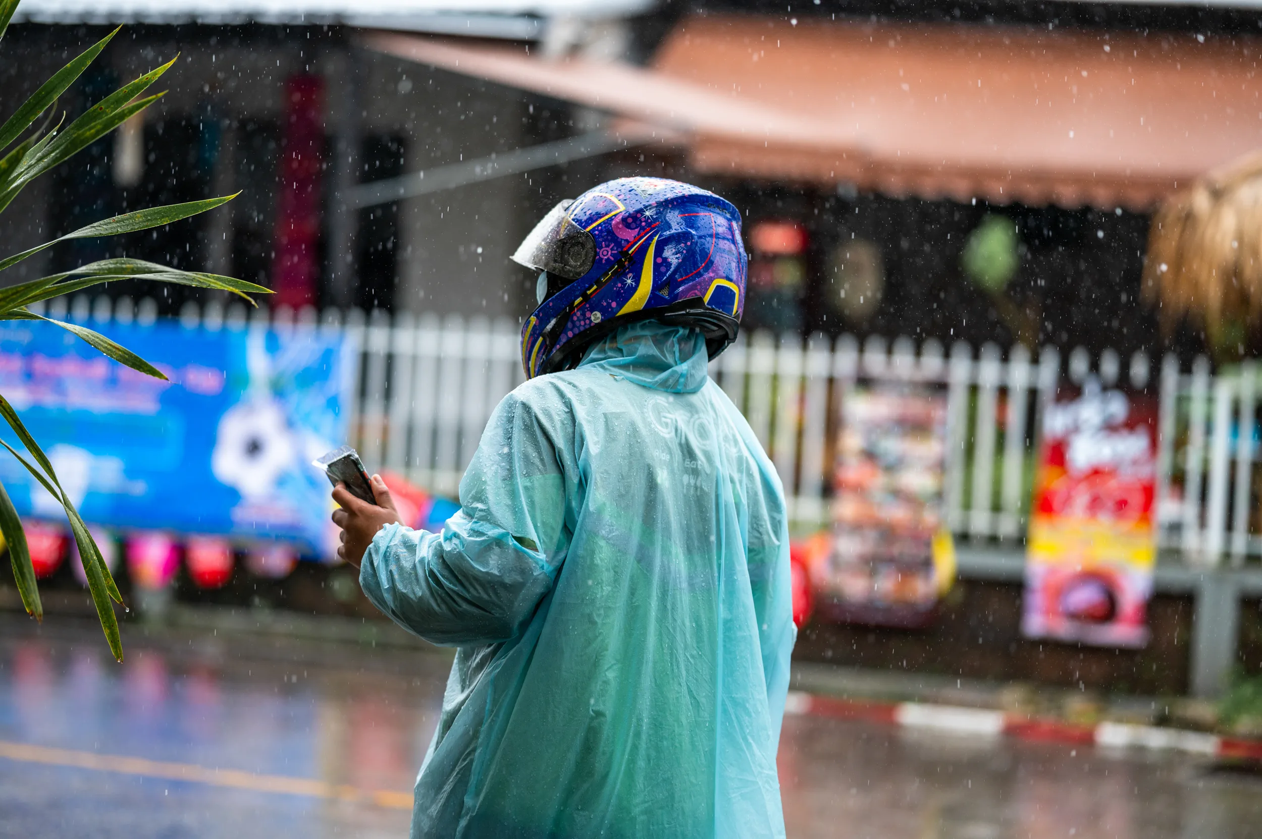 regenzeit thailand (18) Rollerfahrer mit Regencape während einem kurzen Schauer